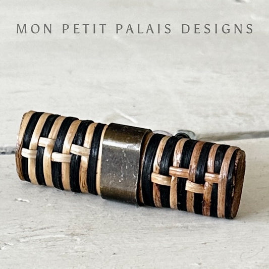 A black and natural rattan T-bar pull with a geometric pattern, branded by MON PETIT PALAIS DESIGNS.