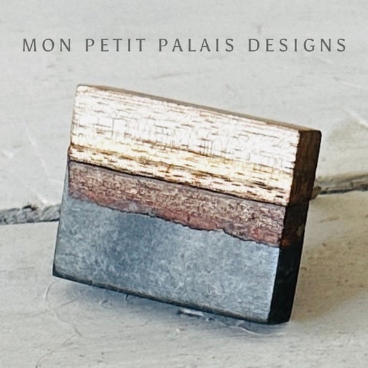 A rectangular cabinet knob with a charcoal resin top and a wood base, branded with 'MON PETIT PALAIS DESIGNS'.