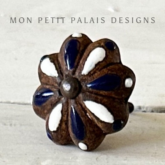 A ceramic knob designed to resemble a flower with blue petals and a brown center, branded with 'MON PETIT PALAIS DESIGNS'.