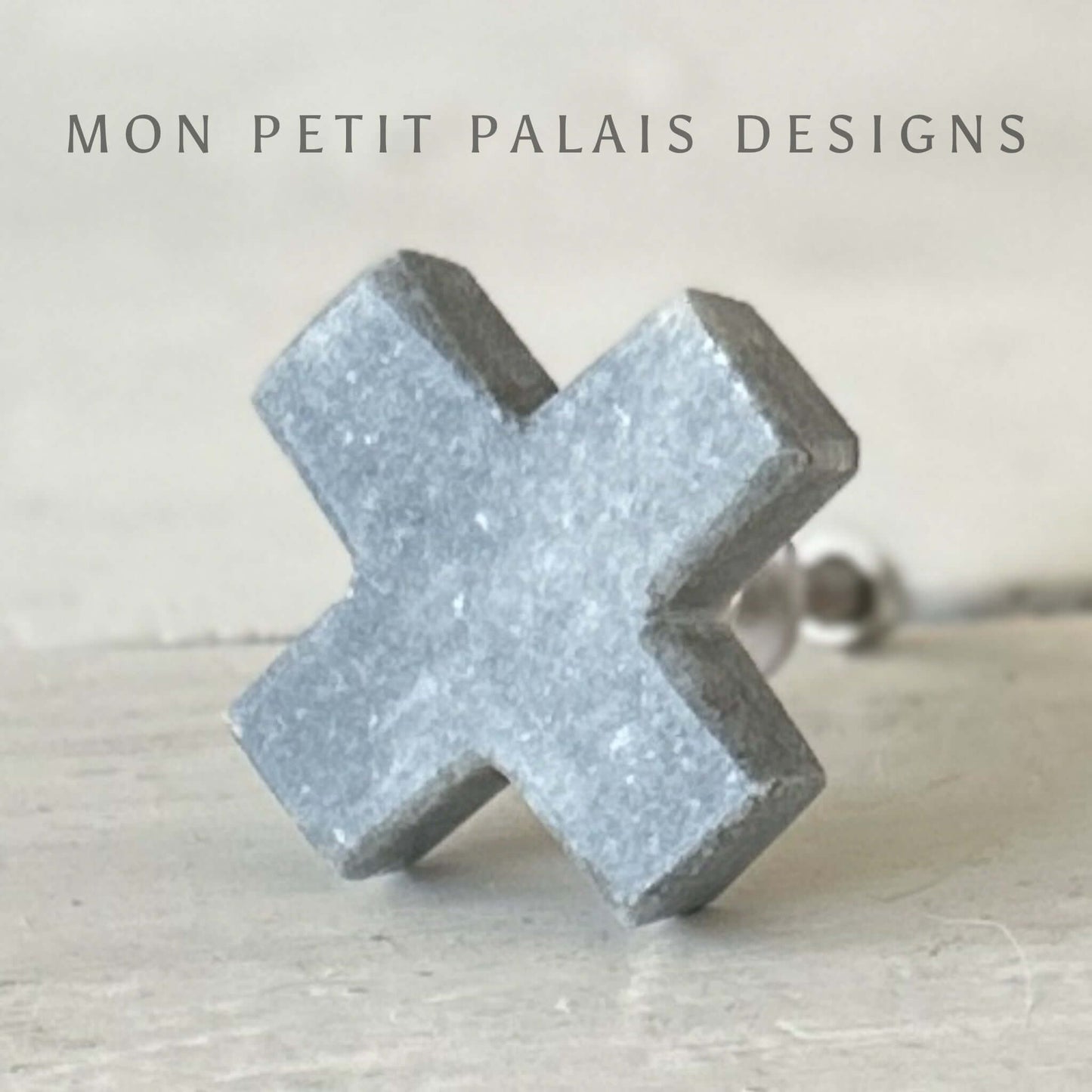 A grey marble cross-shaped knob for furniture.