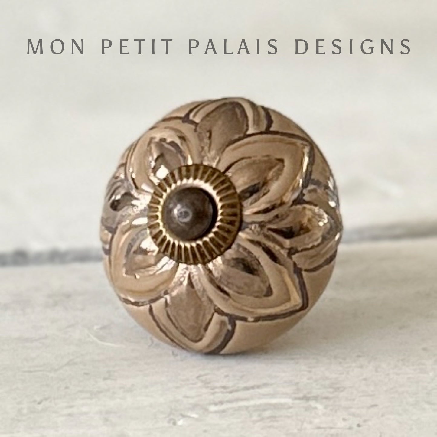 A coffee and gold ceramic knob with a bronze finish, featuring a floral design, branded by MON PETIT PALAIS DESIGNS.