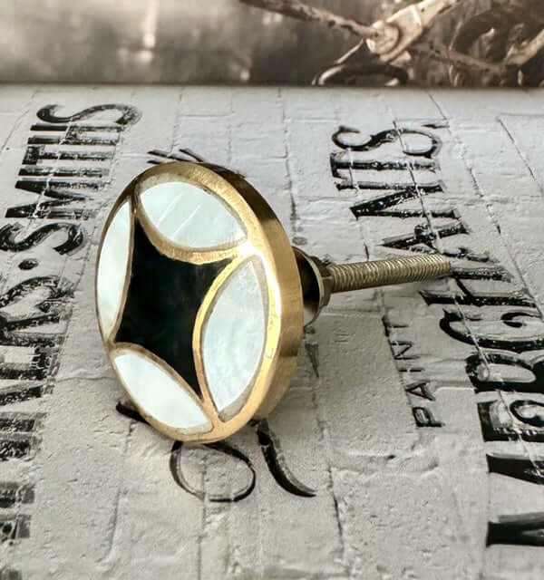 Alex diamond knob shown in moody light with luxe finish - statement drawer pull combining brass, black, and pearl for high end interiors.