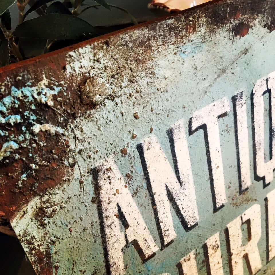Close-up of a rusty, vintage sign showcasing antique aesthetic for Rust & Aged Techniques Workshop.