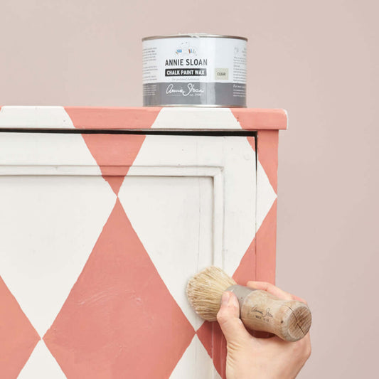 Annie Sloan Clear Chalk Paint™ Wax being applied to a painted cabinet with a brush.