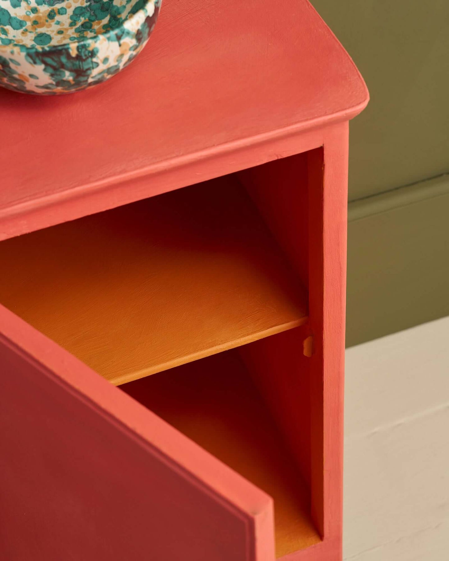 Close-up of cabinet painted in Sandalwood Red with open door showing painted interior shelf.