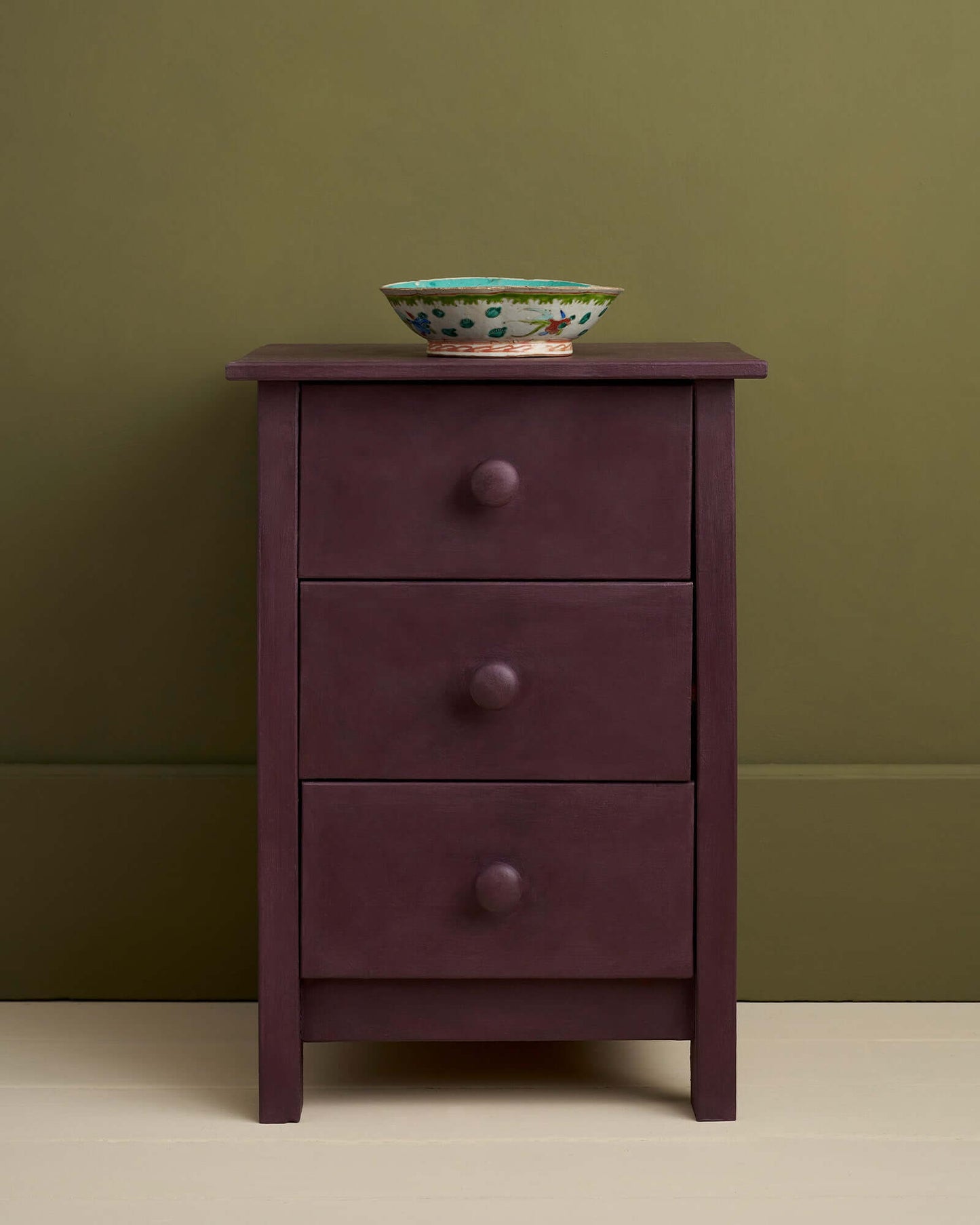 Stylish bedside table painted in Annie Sloan's Tyrian Plum with a decorative bowl on top.