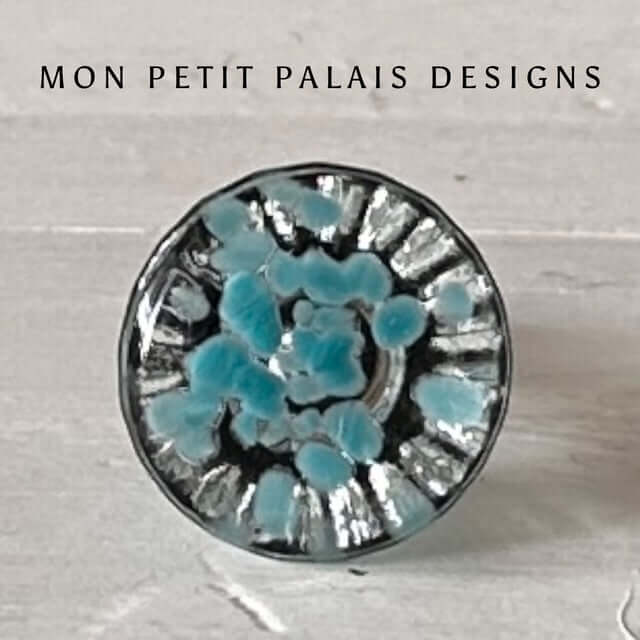 A round blue glass knob with a sunburst-like pattern, branded with 'MON PETIT PALAIS DESIGNS'.