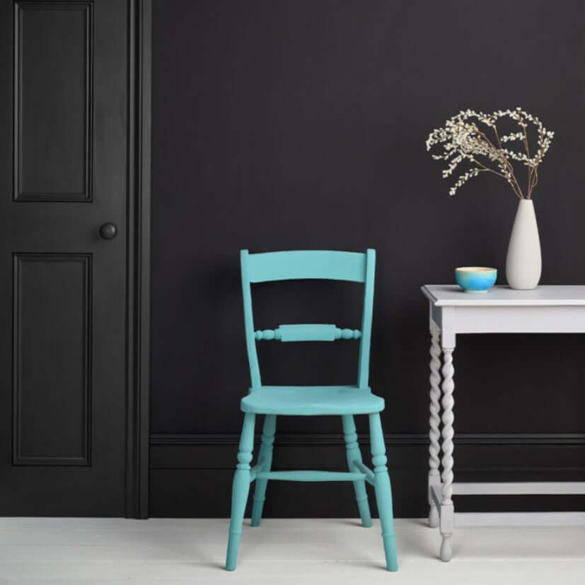 Athenian Black - Annie Sloan Satin Paint used on the wall behind a turquoise chair and white table.