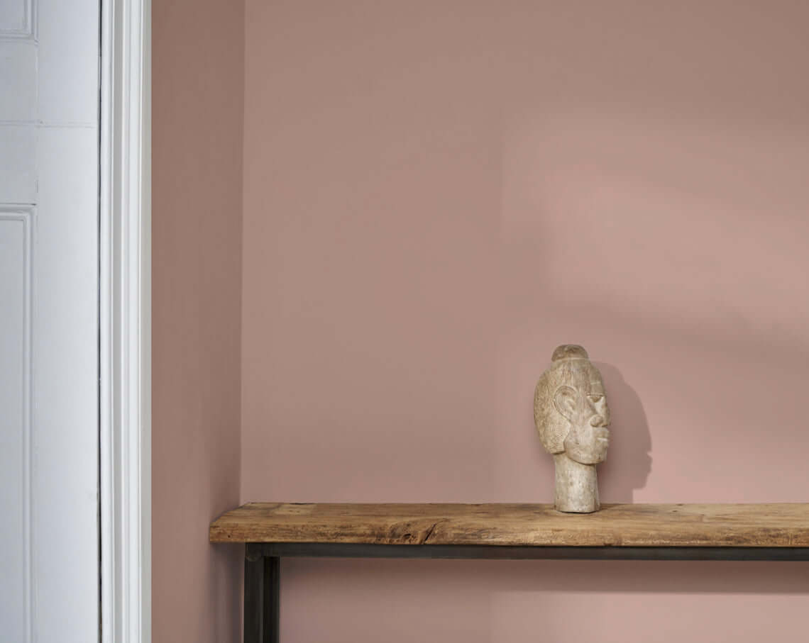 Piranesi Pink wall paint by Annie Sloan with a decorative sculpture on a wooden shelf.