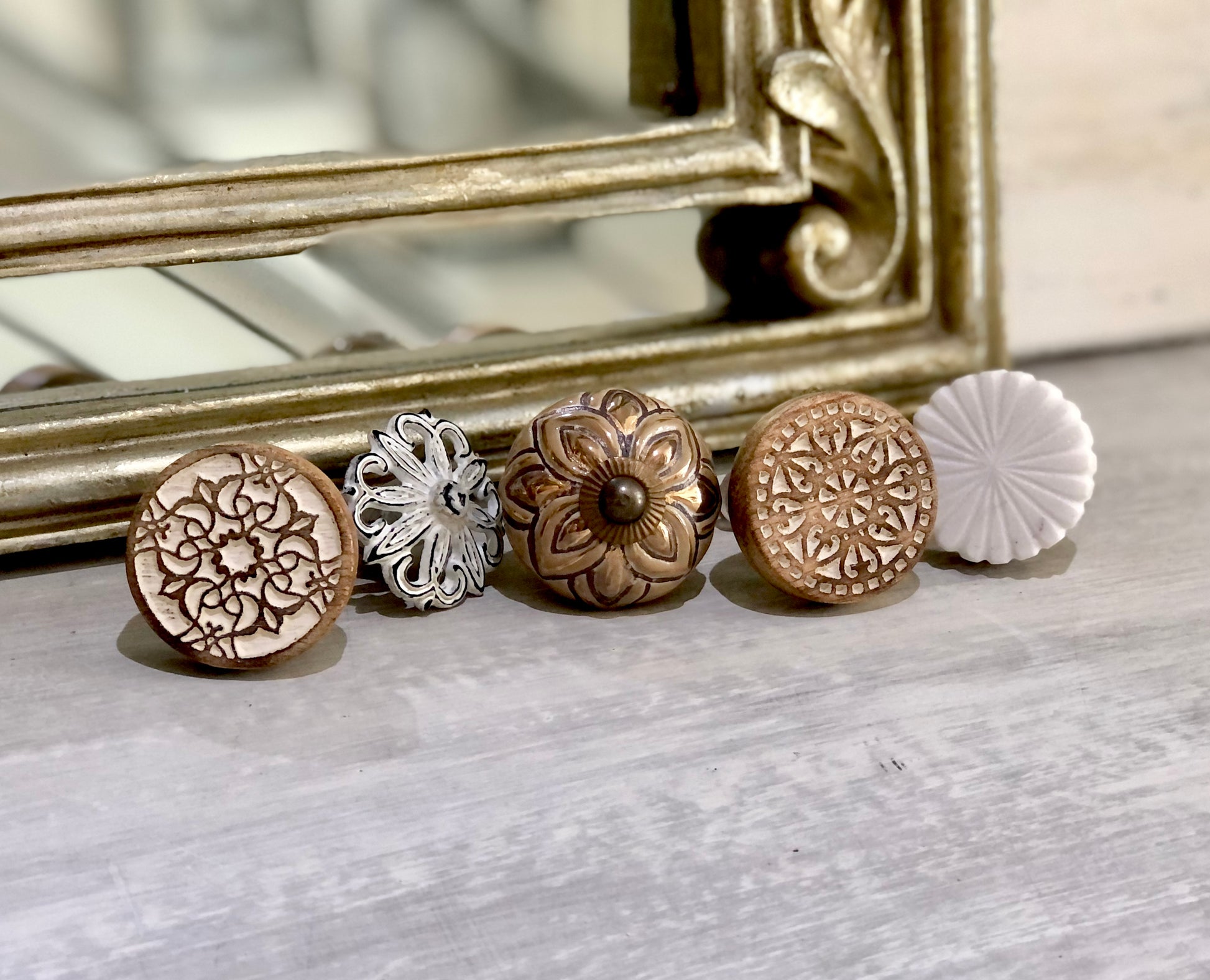 A curated collection of decorative knobs in carved wood, ceramic, and metal - coastal boho hardware styled with a vintage gold frame, from Mon Petit Palais Designs.