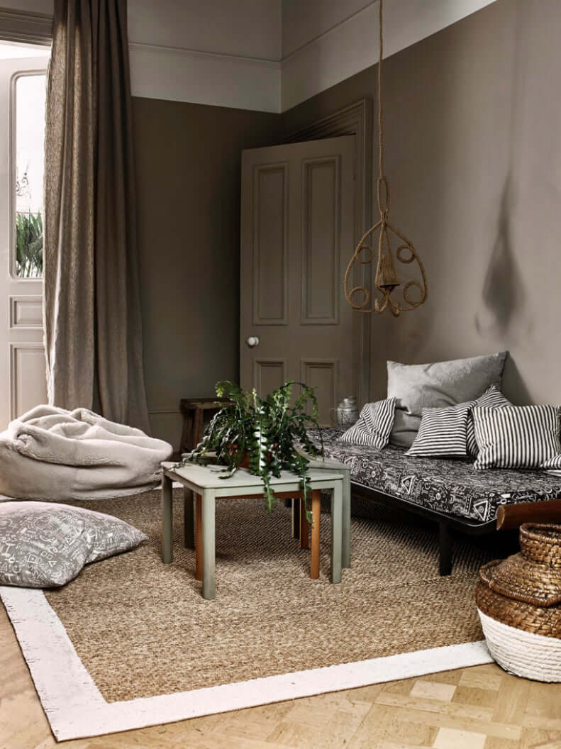 Cozy living room with French Linen walls, patterned sofa, and natural textures for a serene atmosphere.