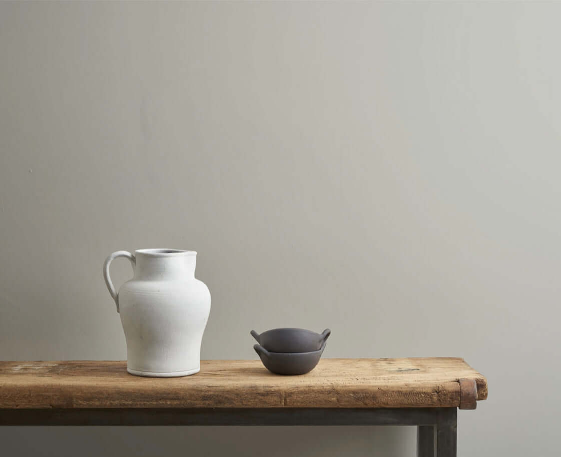 Doric - Annie Sloan Wall Paint used in a neutral setting featuring a white jug and a dark bowl on a wooden table.