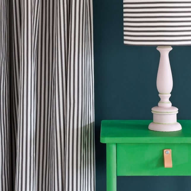 Emerald green chalk-painted console table detail against striped fabric, finished in Annie Sloan Antibes Green.