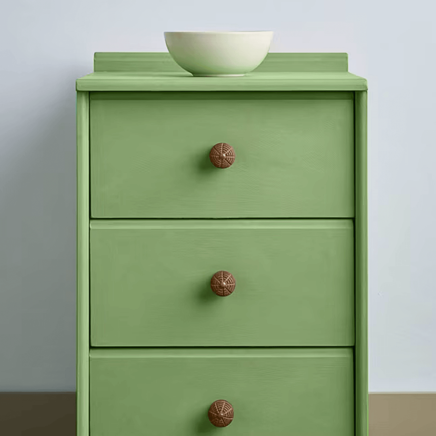 Capability Green Annie Sloan Chalk Paint used on a three-drawer dresser with wooden knobs and a bowl on top.
