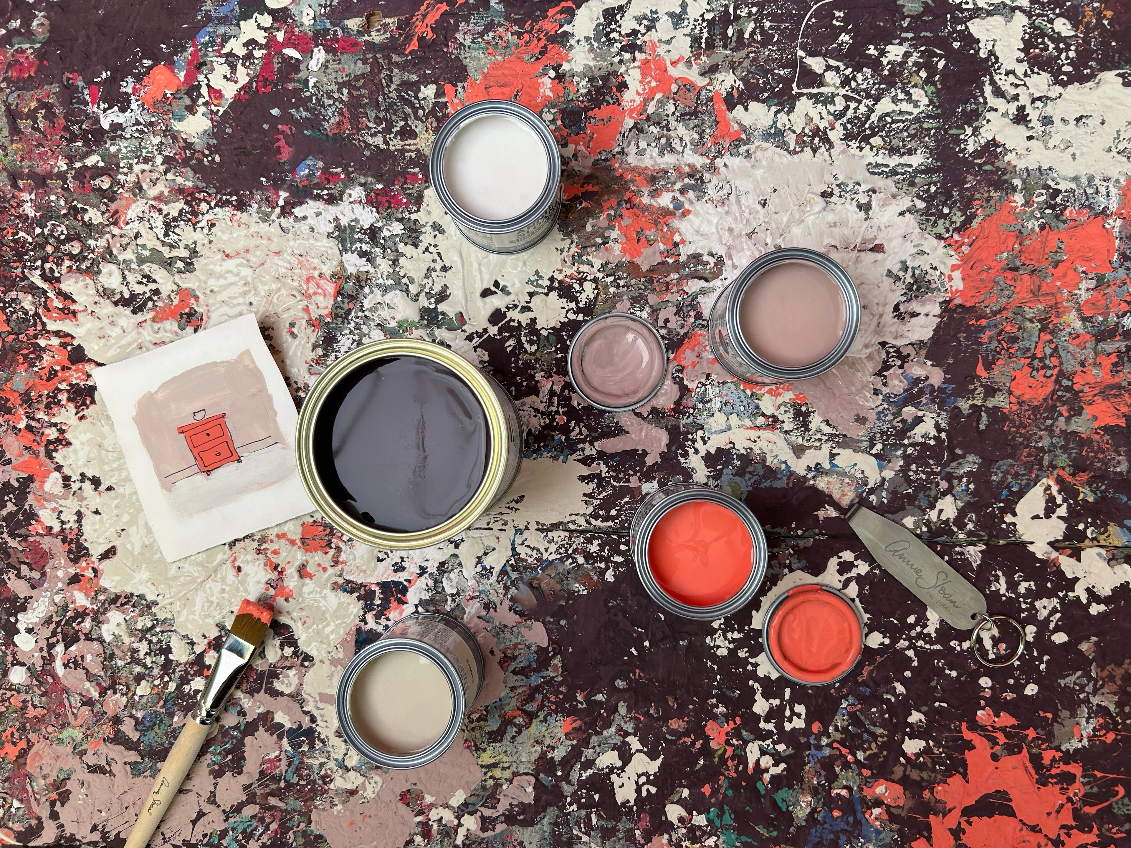 Assorted paint cans on a textured surface with artistic brush strokes