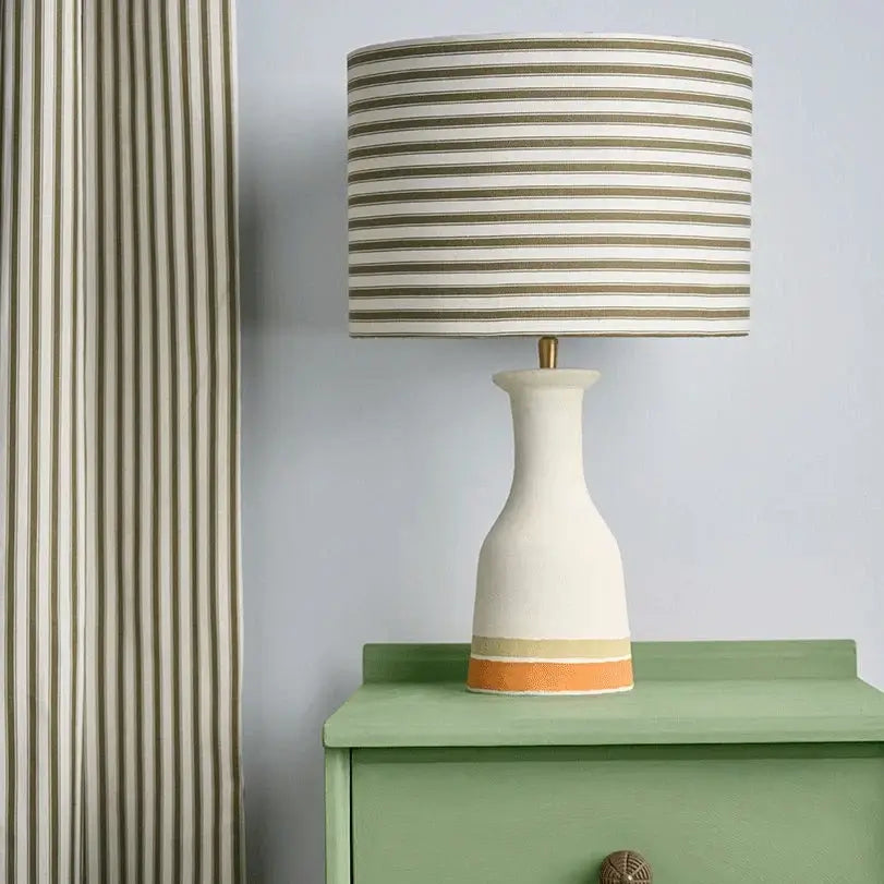 Stylish lamp with a striped shade on a green painted dresser, ideal for upcycling and adding elegance to space.