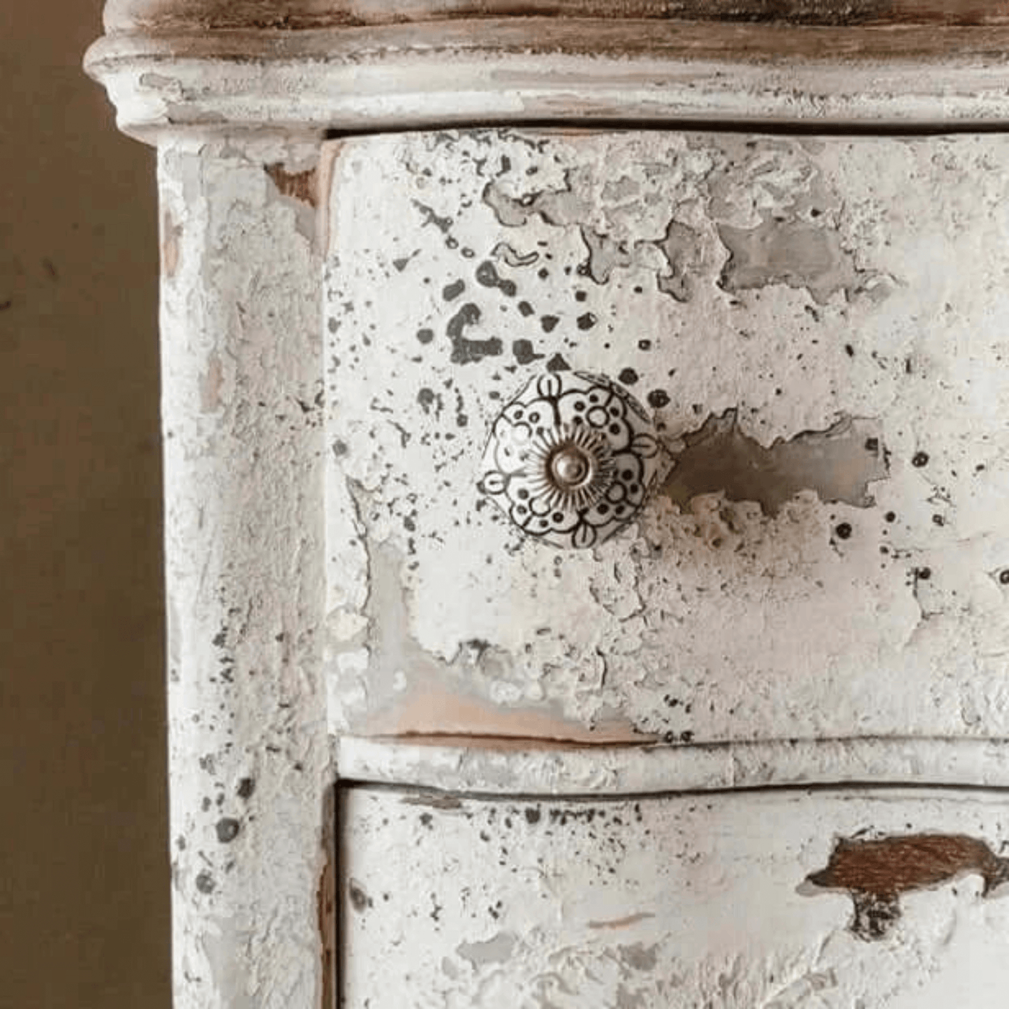 Distressed wooden drawer with a decorative knob on a beige background