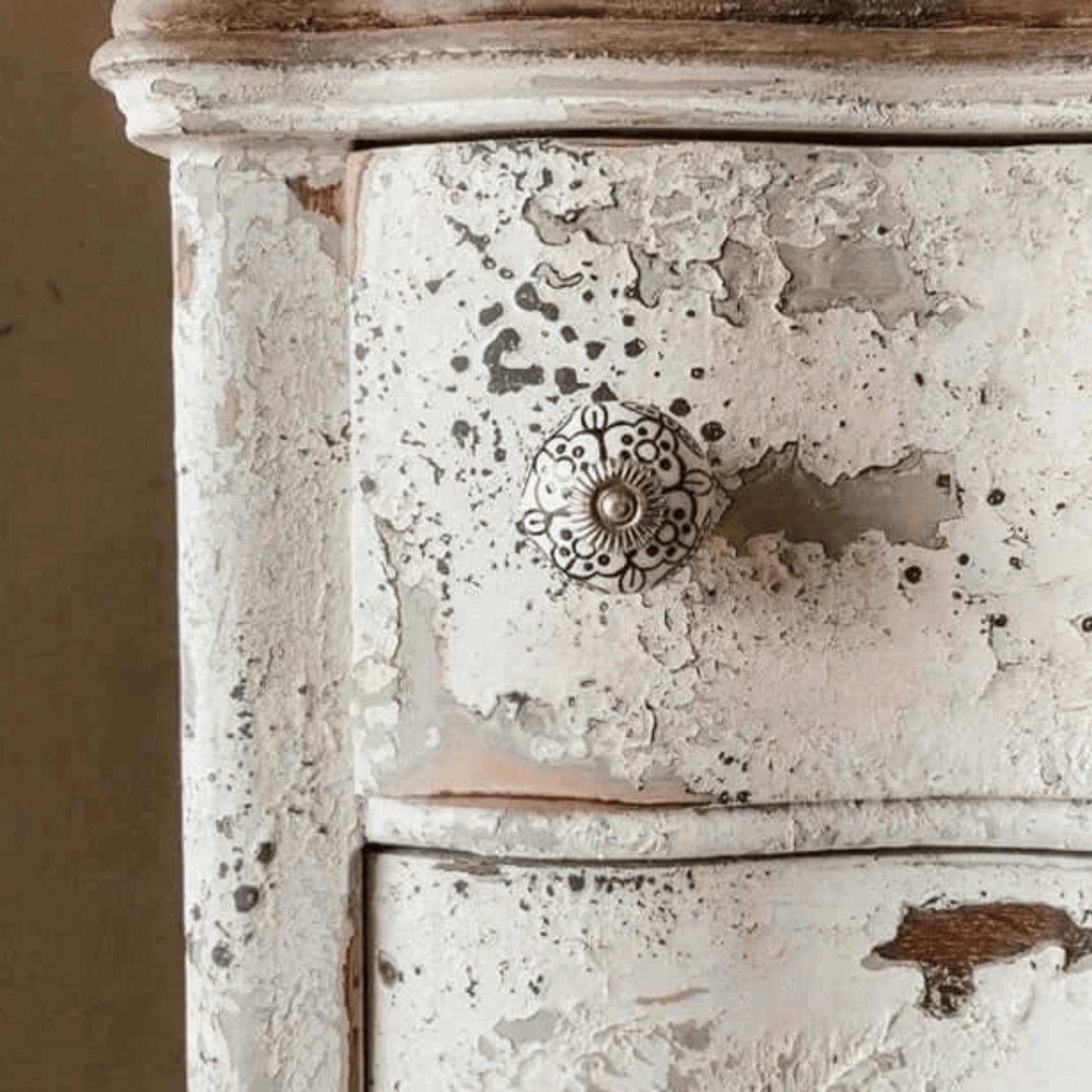 Distressed wooden drawer with a decorative knob on a beige background