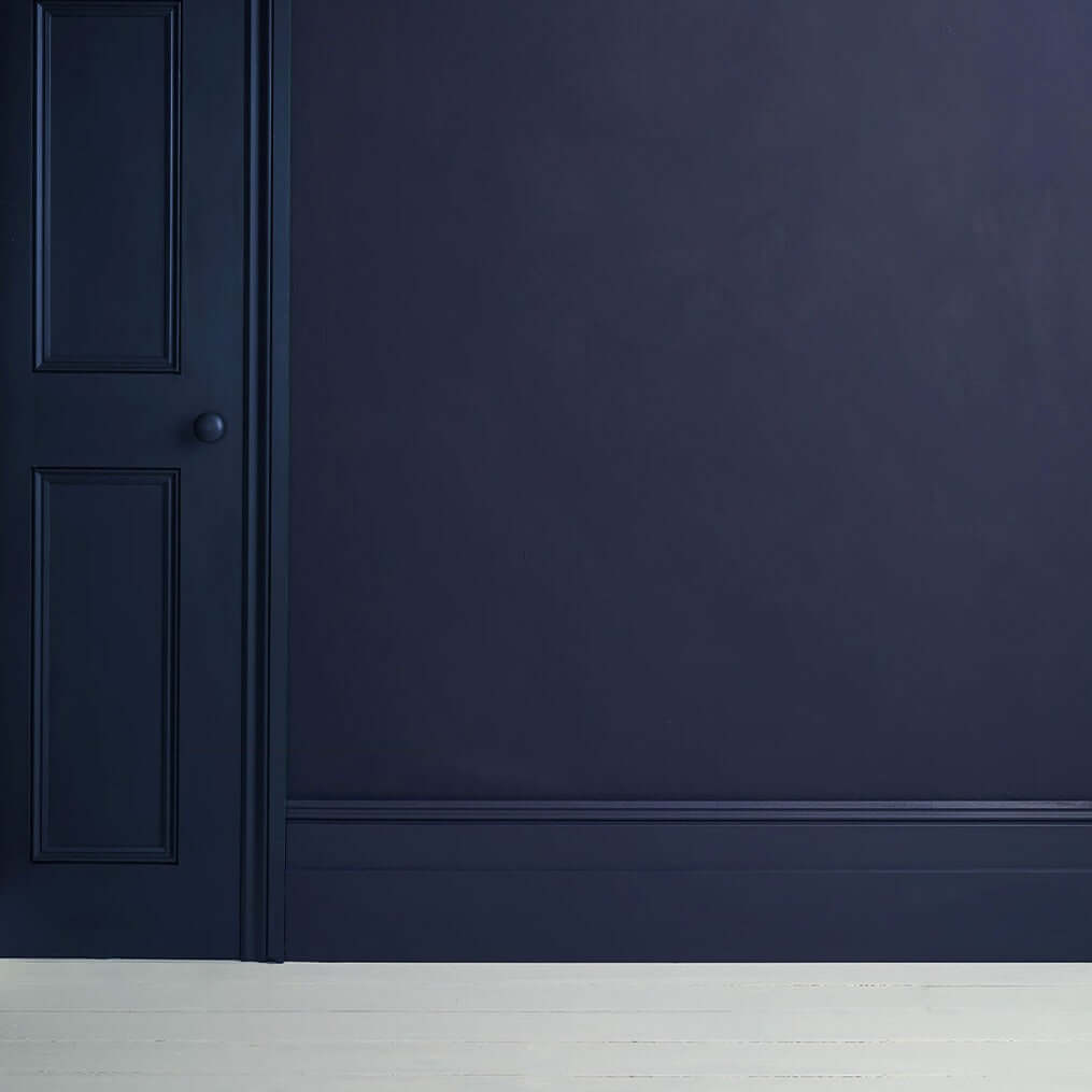 Oxford Navy - Annie Sloan Satin Paint on a wall with a door, showcasing a rich, elegant navy-blue finish.