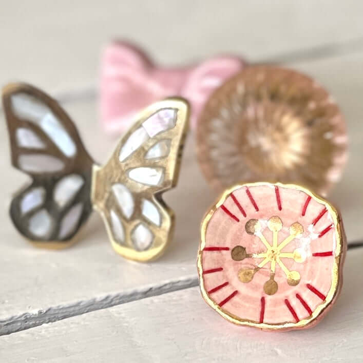 Styled ceramic knobs including blush & gold floral knob with butterfly design.