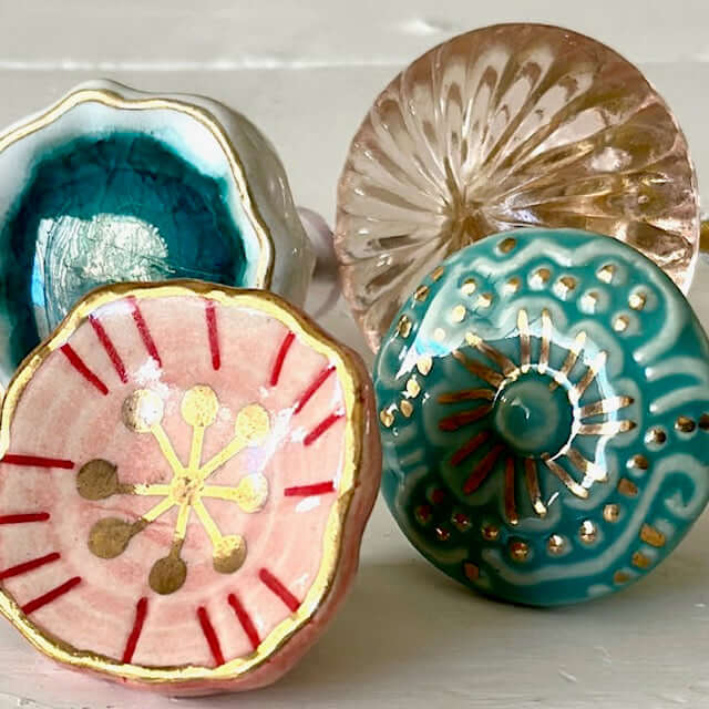 Group of decorative knobs including blush floral knob, turquoise ceramic, and glass designs.
