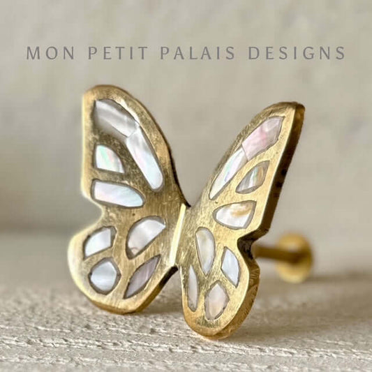 Side view of butterfly brass cabinet knob with shimmering mother of pearl wings, vintage decorative furniture hardware. 
