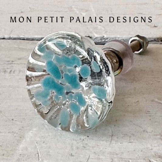 Glass knob with blue speckles on a light background, featuring 'Mon Petit Palais Designs' text.