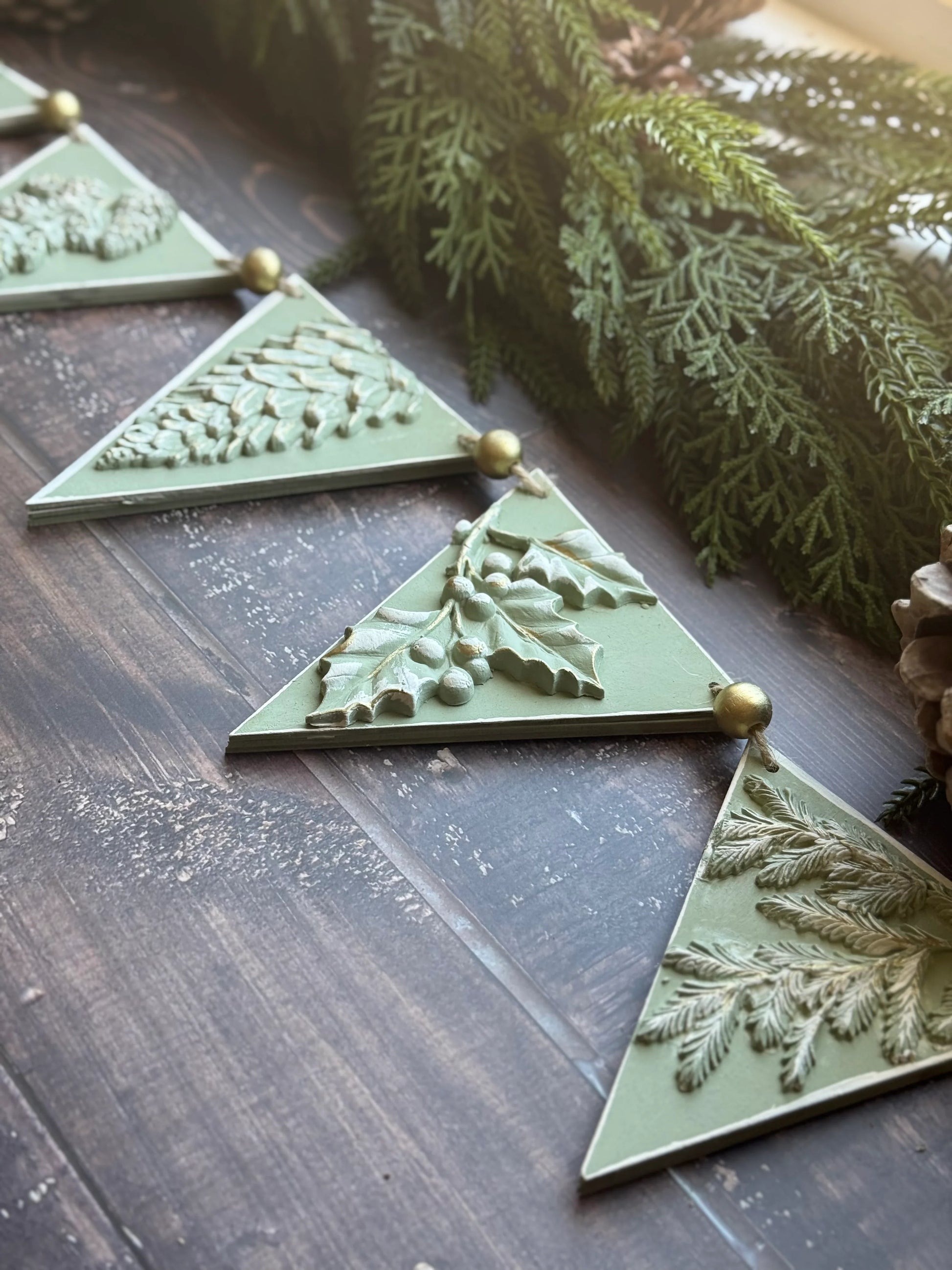 IOD Winter Forage Decor Mould™ decorative elements featuring pinecones and foliage on a rustic wooden surface.
