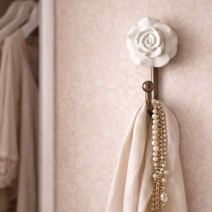 White Ceramic Rose Hook holding a scarf and pearls on a vintage-style wall.