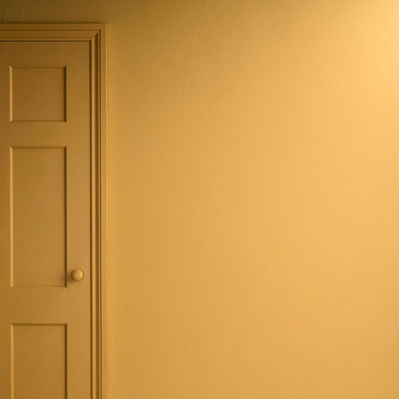 Carnaby Yellow - Annie Sloan Satin Paint on a wall and door, showcasing a rich mustard yellow color.