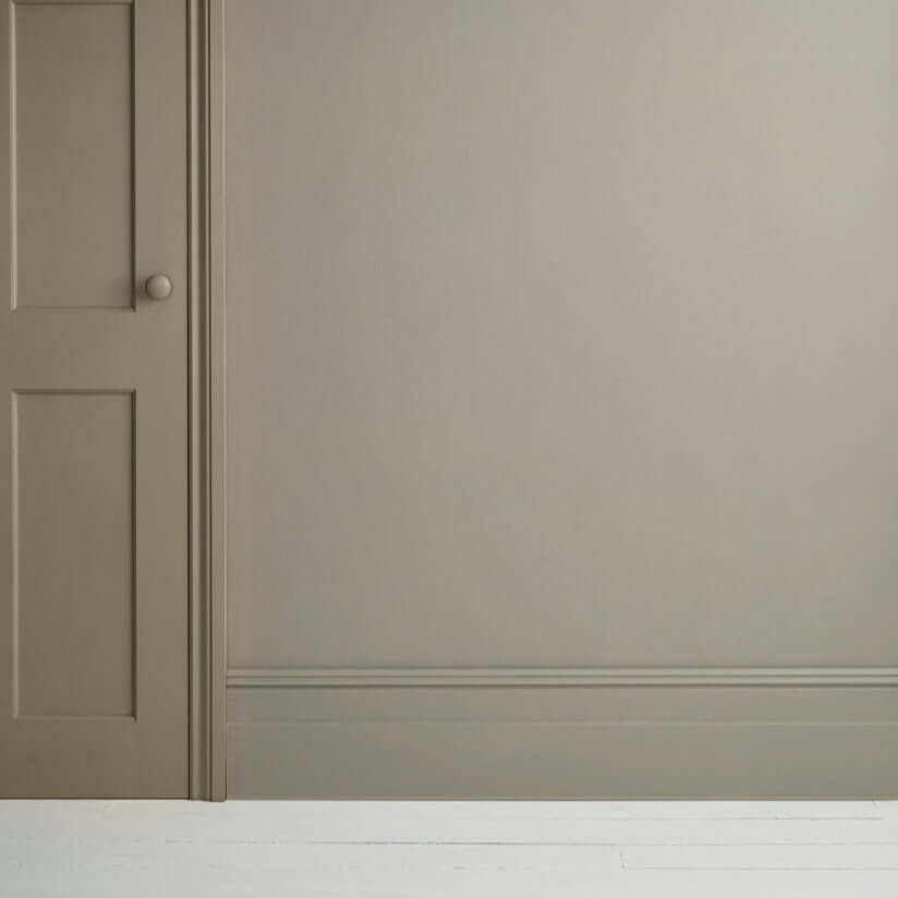 French Linen - Annie Sloan Satin Paint on a wall beside a door, showcasing a warm greige tone.