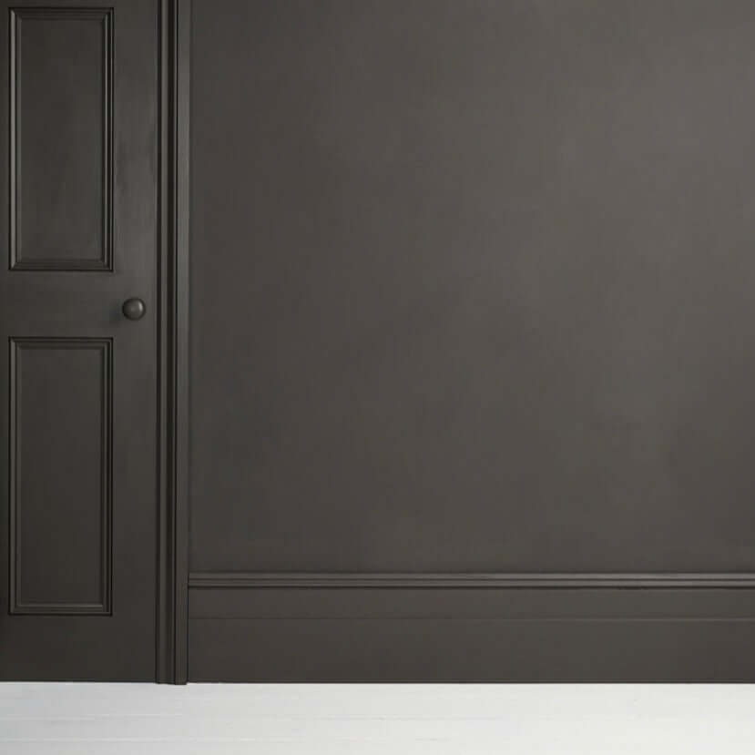 Graphite - Annie Sloan Satin Paint applied to a wall with a door, showcasing a dark grey chalkboard-like finish.